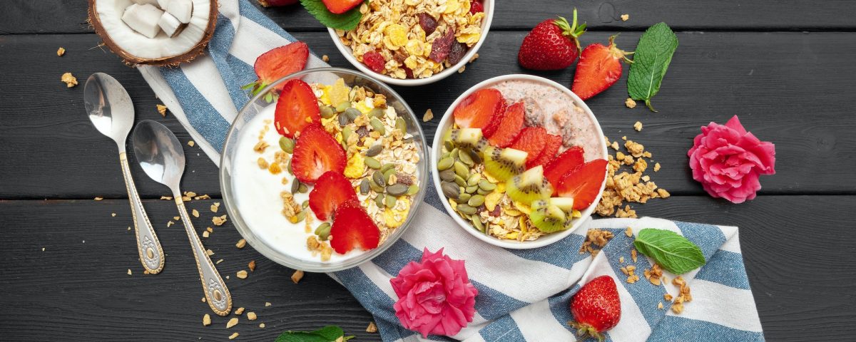 Home-made Yoghurt with granola, fruit and coconut top view on wooden background